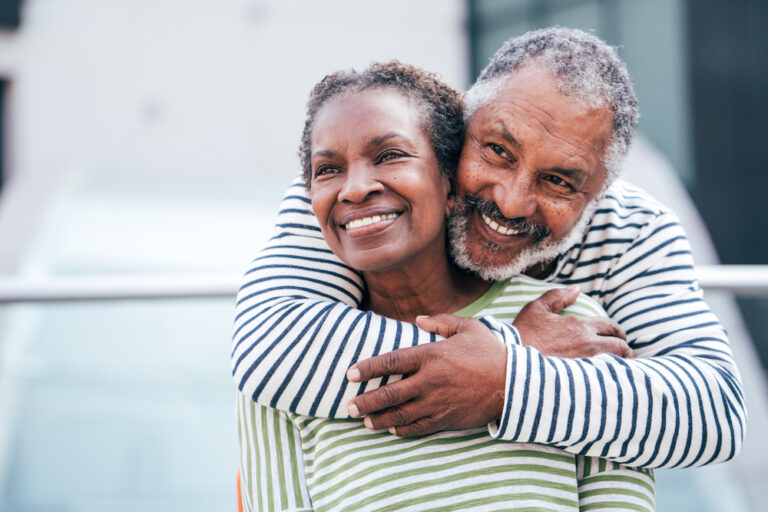 Self care expressed through love, with an older African American man and woman embracing and smiling