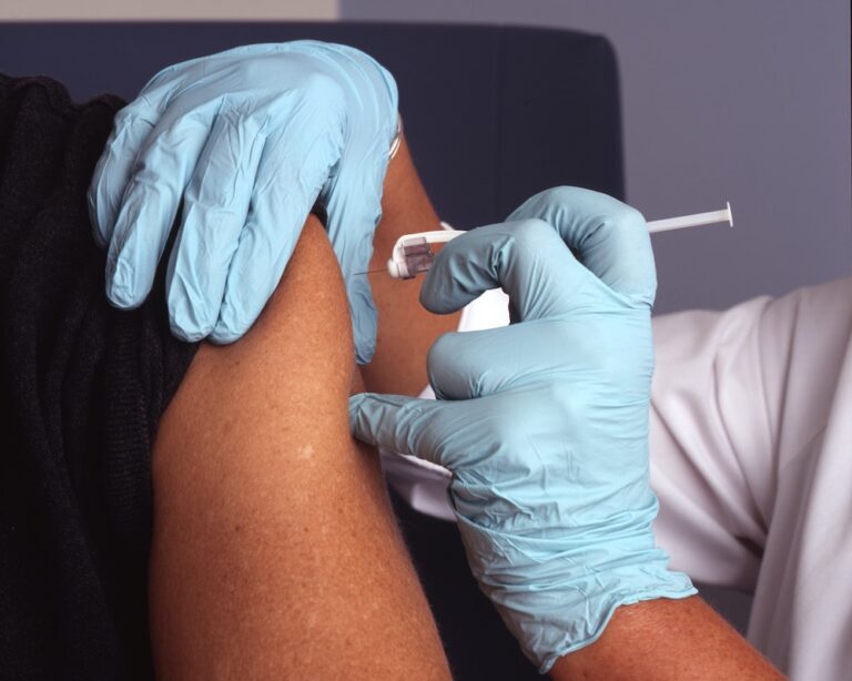 A vaccine shot being inserted into a Black patient's arm