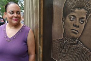 Ida. B Wells great-granddaughter Michelle Duster stands next to a plaque of her at The Truth of Light monument.